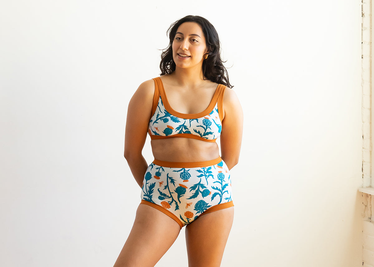 Model wearing a set of Thunderpants Bralette and Sky Rise style underwear in an artichoke print - turquoise and copper colors.