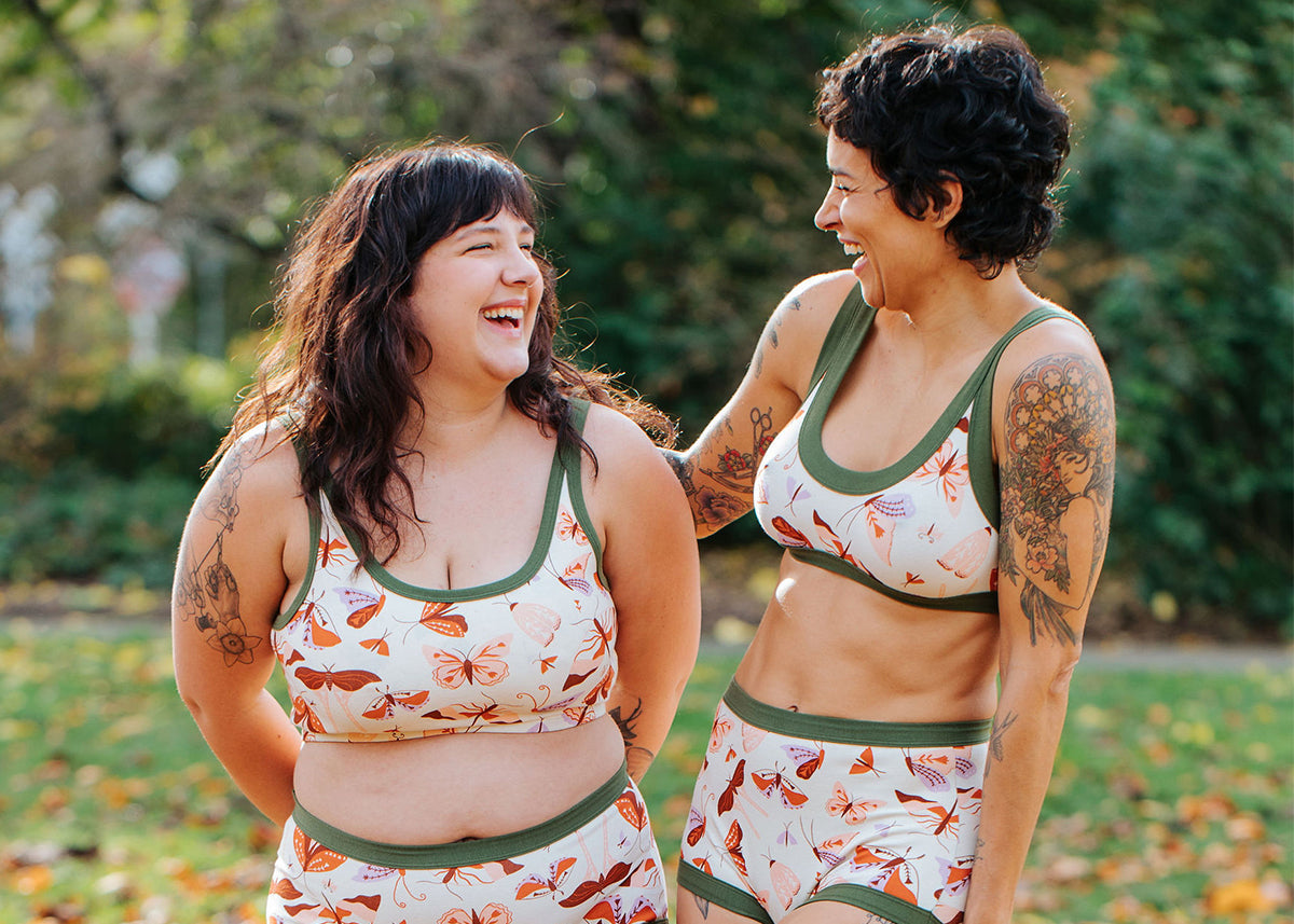 Two Models wearing various Thunderpants Bra styles in Field Study print - pink, orange, brown, and purple moths.