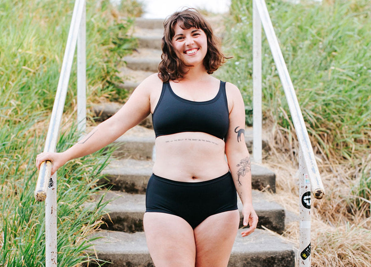 Model smiling wearing Thunderpants Swimwear in Black Top and Original style bottoms.