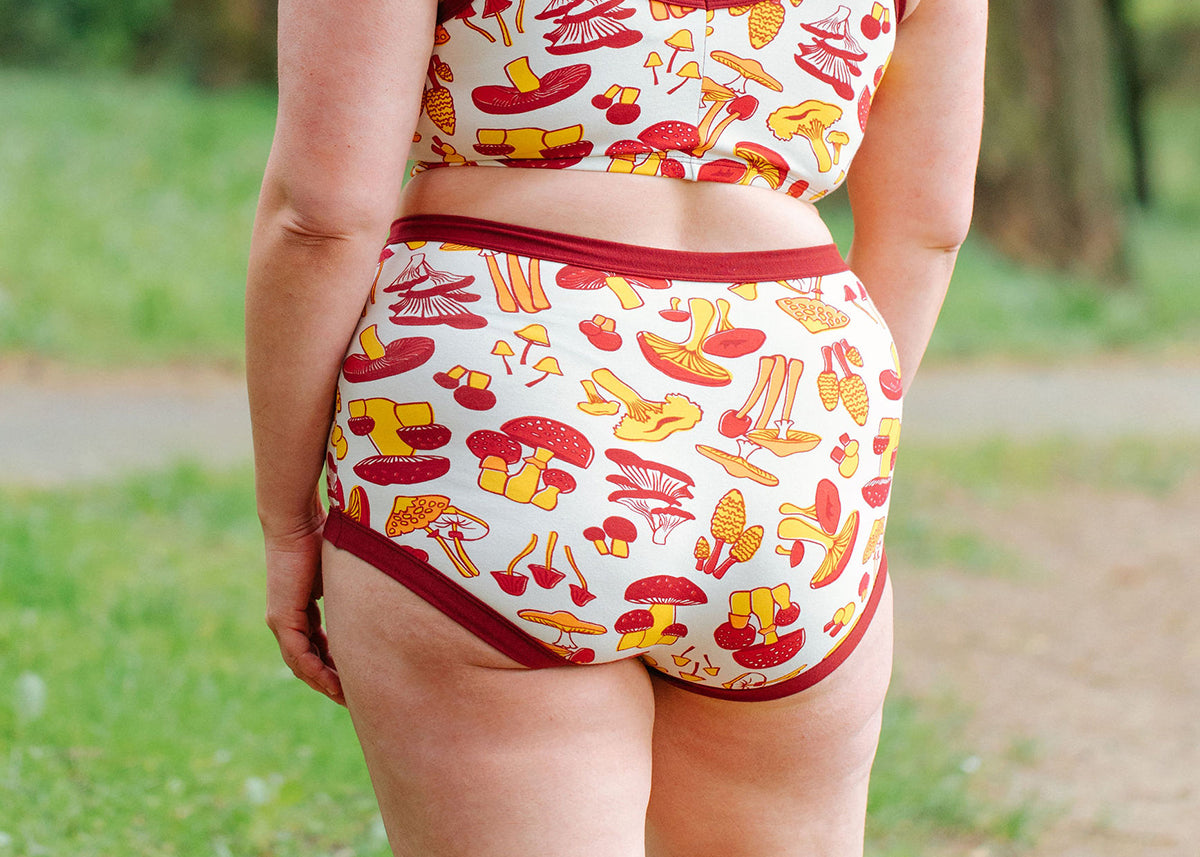 Model wearing Thunderpants Sky Rise style underwear in Whadda Fungi - red, orange, and yellow mushrooms.