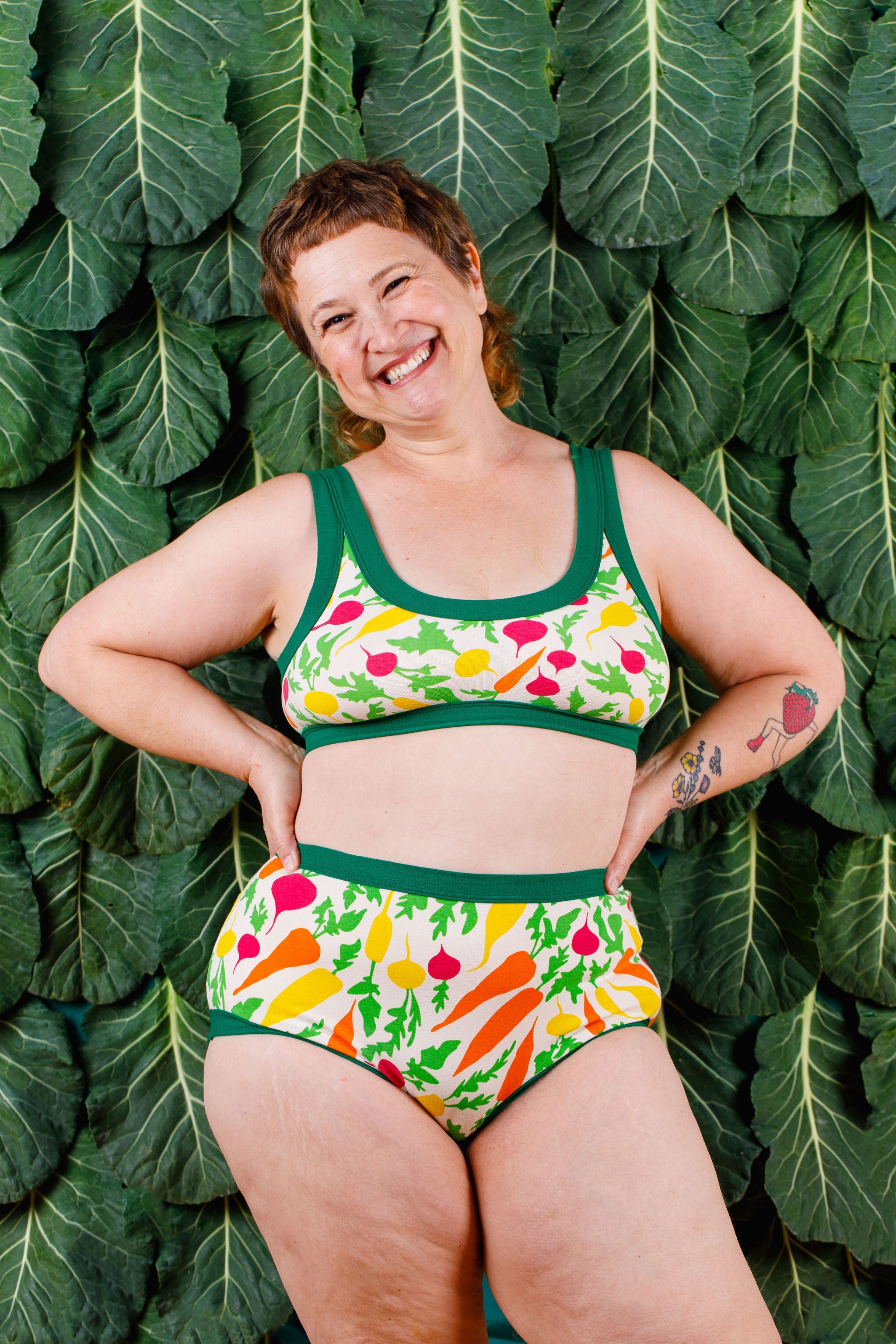 Model standing in front of a kale wall wearing Thunderpants Original style underwear and Bralette in Root Veggies.