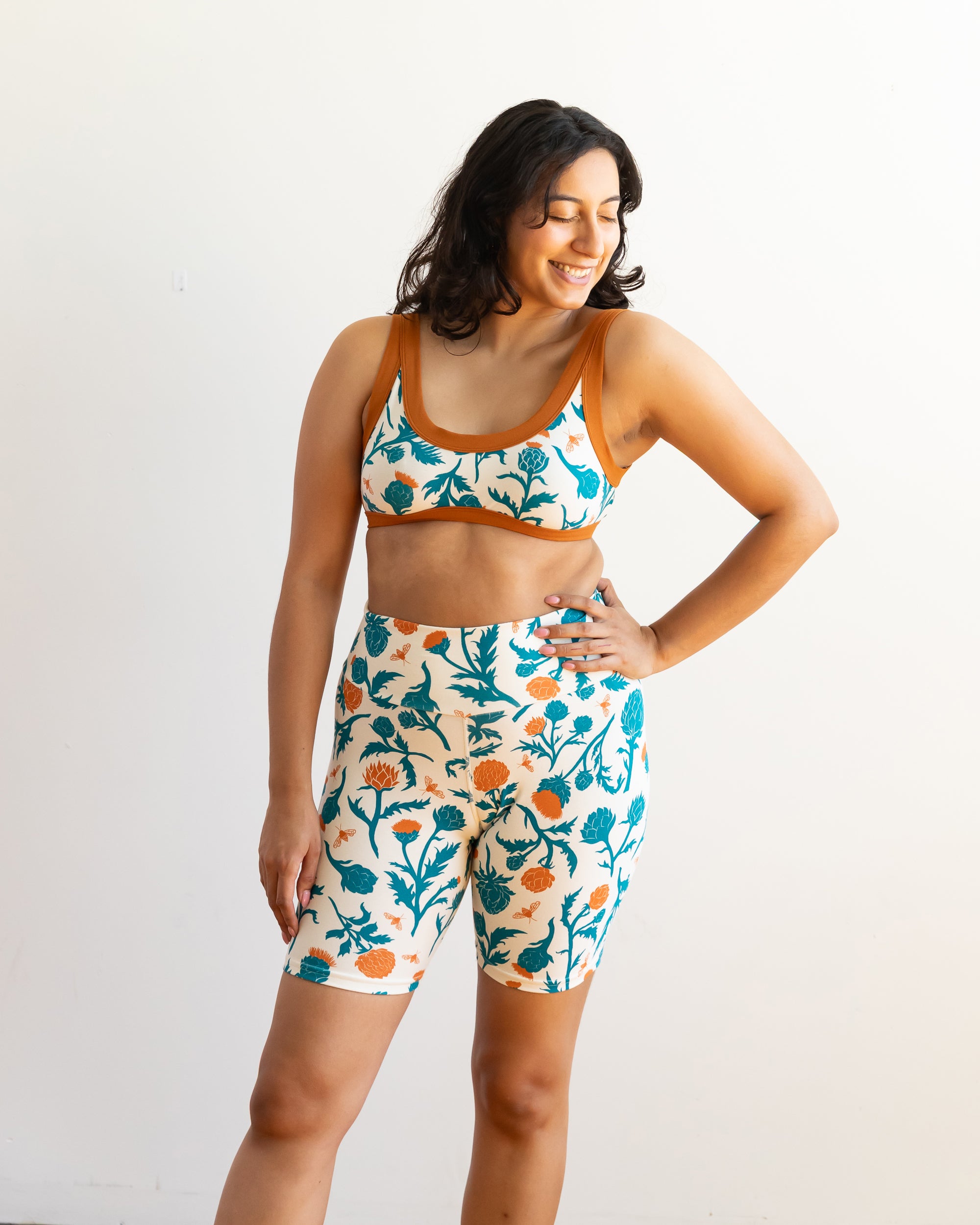 Model wearing Thunderpants Bike Shorts and Bralette in Robben's Artichokes print - teal and rust artichokes and bees.