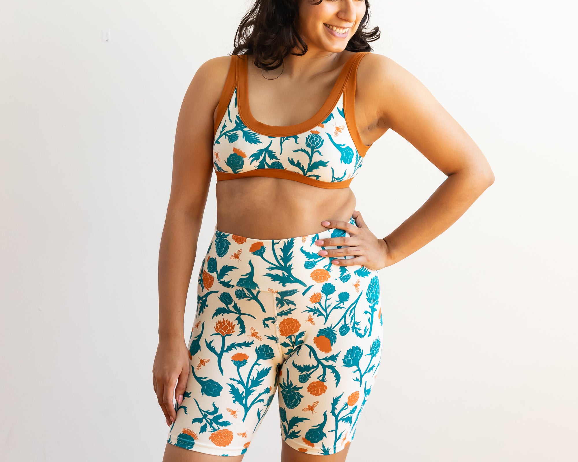 Model wearing Thunderpants Bike Shorts and Bralette in Robben's Artichokes print - teal and rust artichokes and bees.