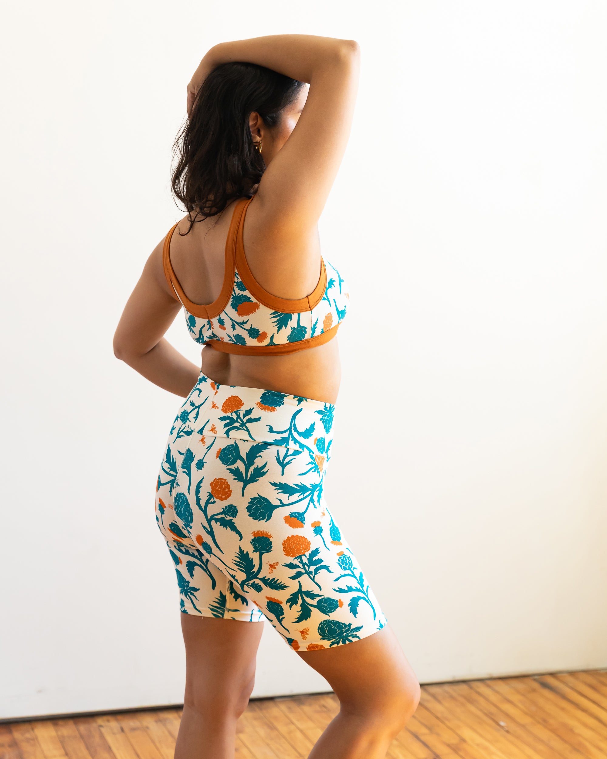 Model wearing Thunderpants Bike Shorts and Bralette in Robben's Artichokes print - teal and rust artichokes and bees.