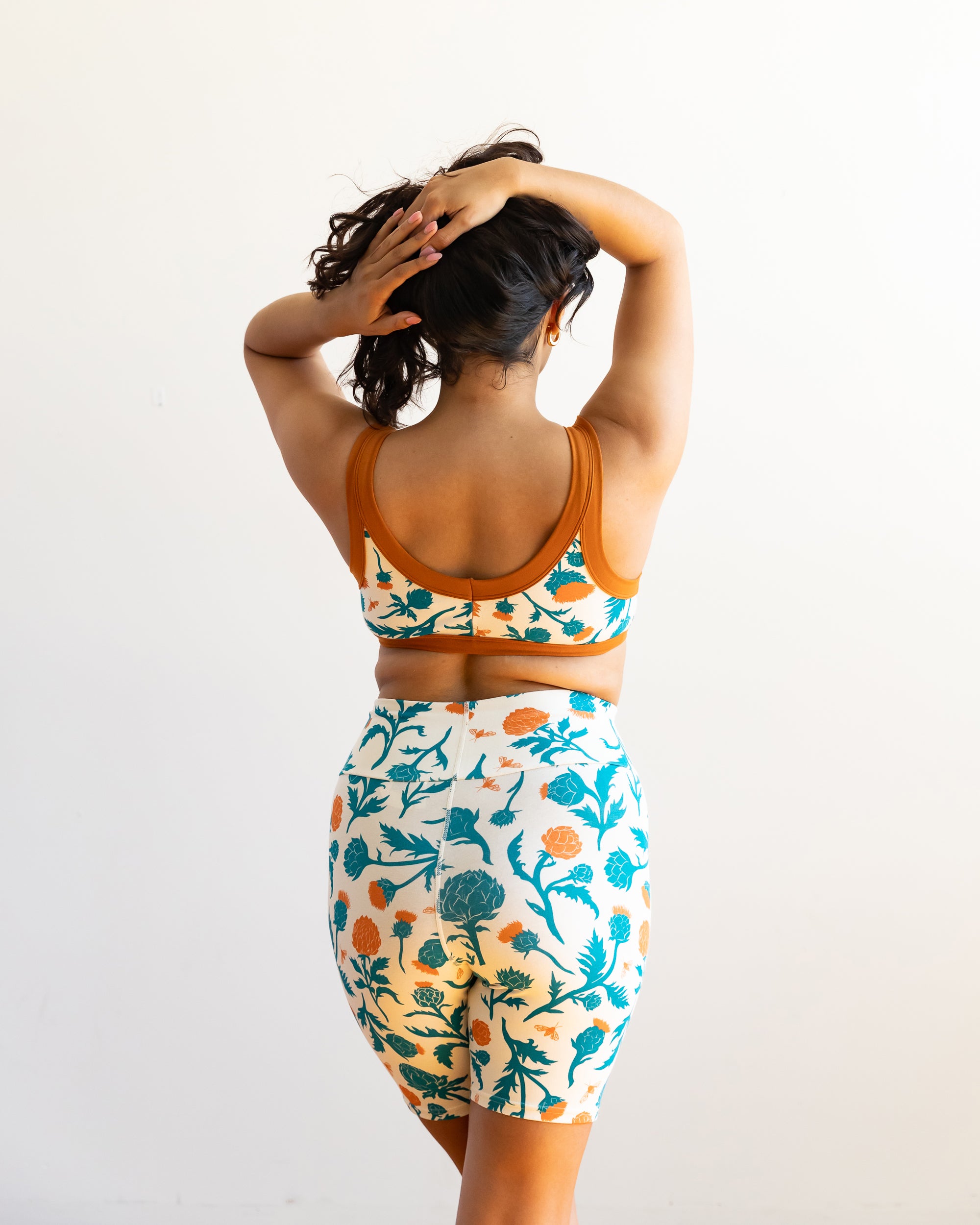 Model wearing Thunderpants Bike Shorts and Bralette in Robben's Artichokes print - teal and rust artichokes and bees.