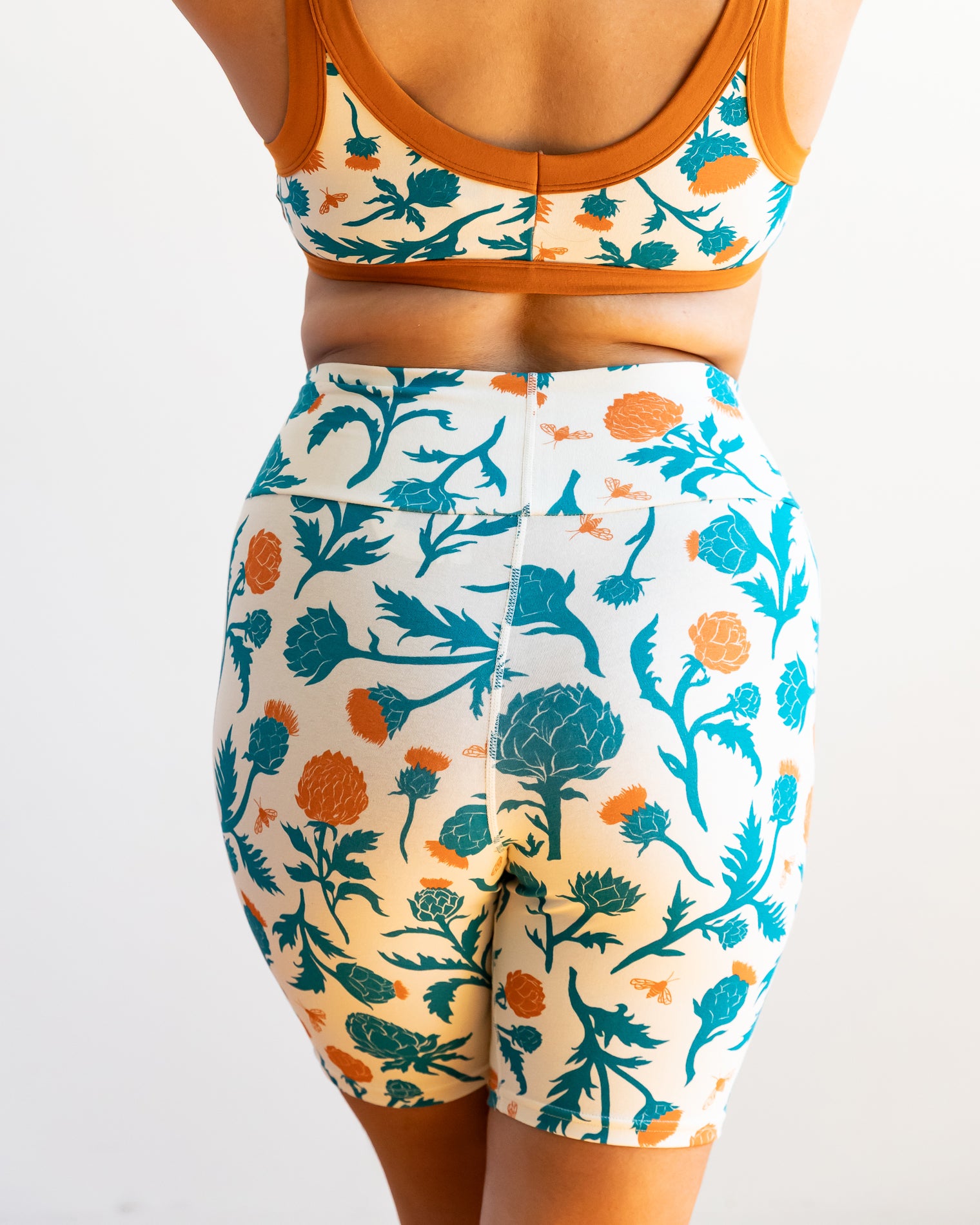 Model wearing Thunderpants Bike Shorts and Bralette in Robben's Artichokes print - teal and rust artichokes and bees.