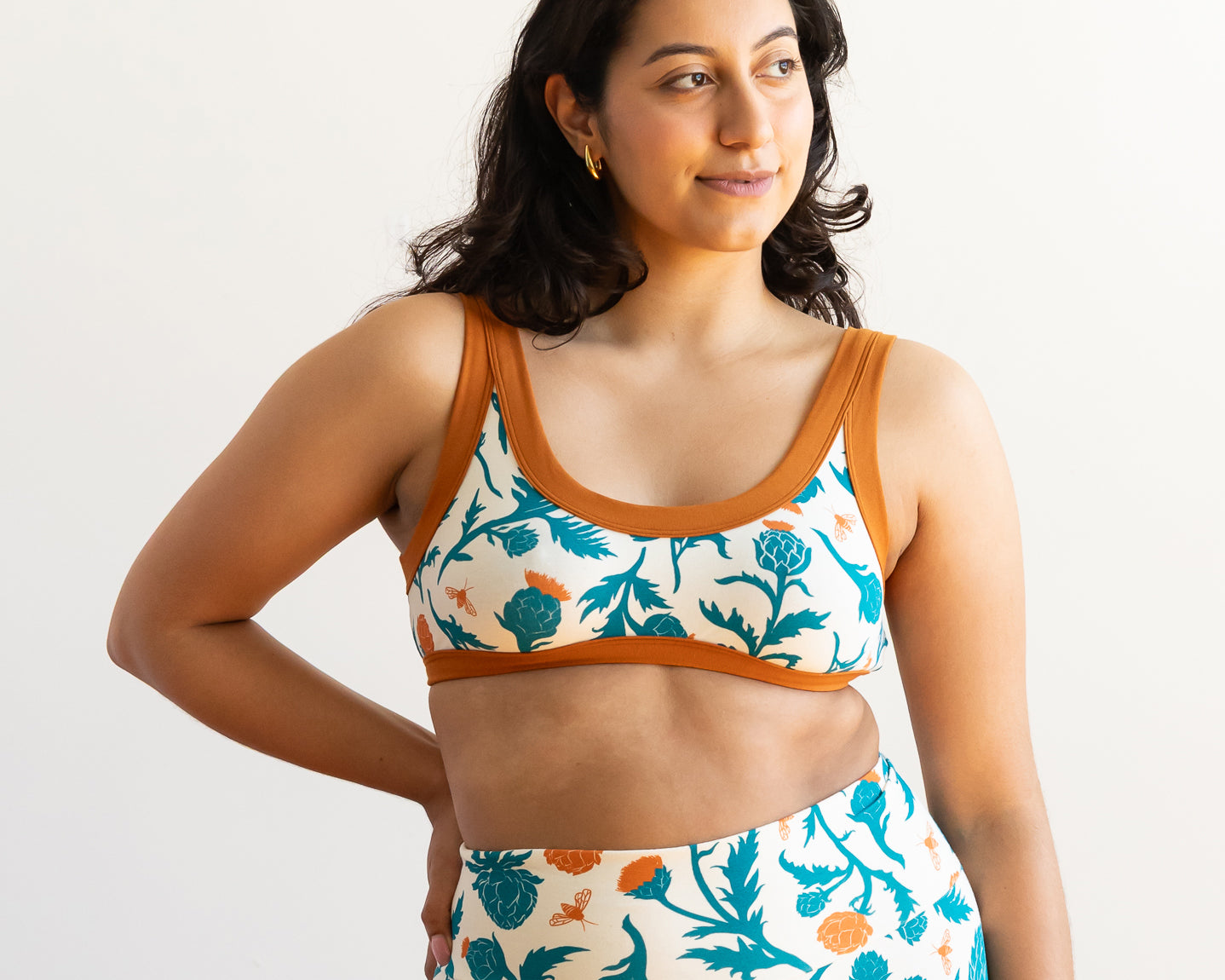 Model wearing Thunderpants Bralette and Bike Shorts in Robben's Artichokes print - teal and rust artichokes and bees.