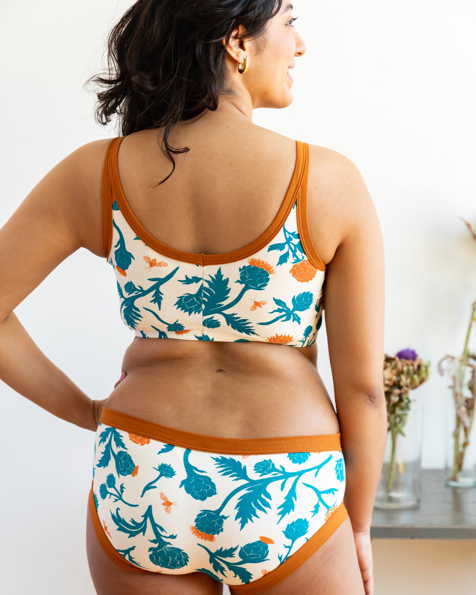 Model wearing Thunderpants Longline Bra and Hipster style underwear in Robben's Artichokes print - teal and rust artichokes and bees.