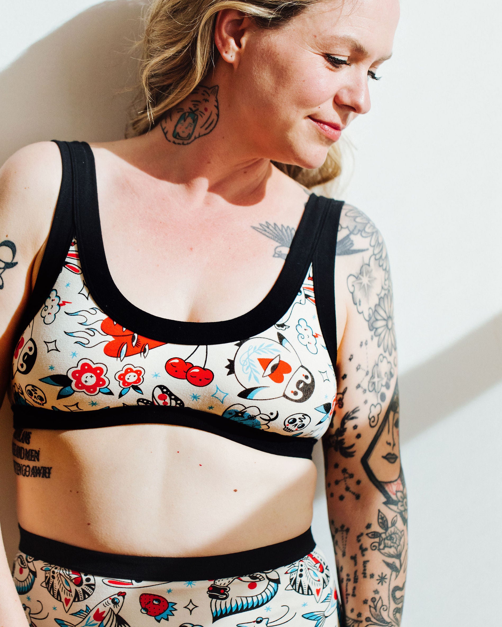 Model wearing Thunderpants Bralette in Inked Up - a tattoo pattern with black, red, and blue. 