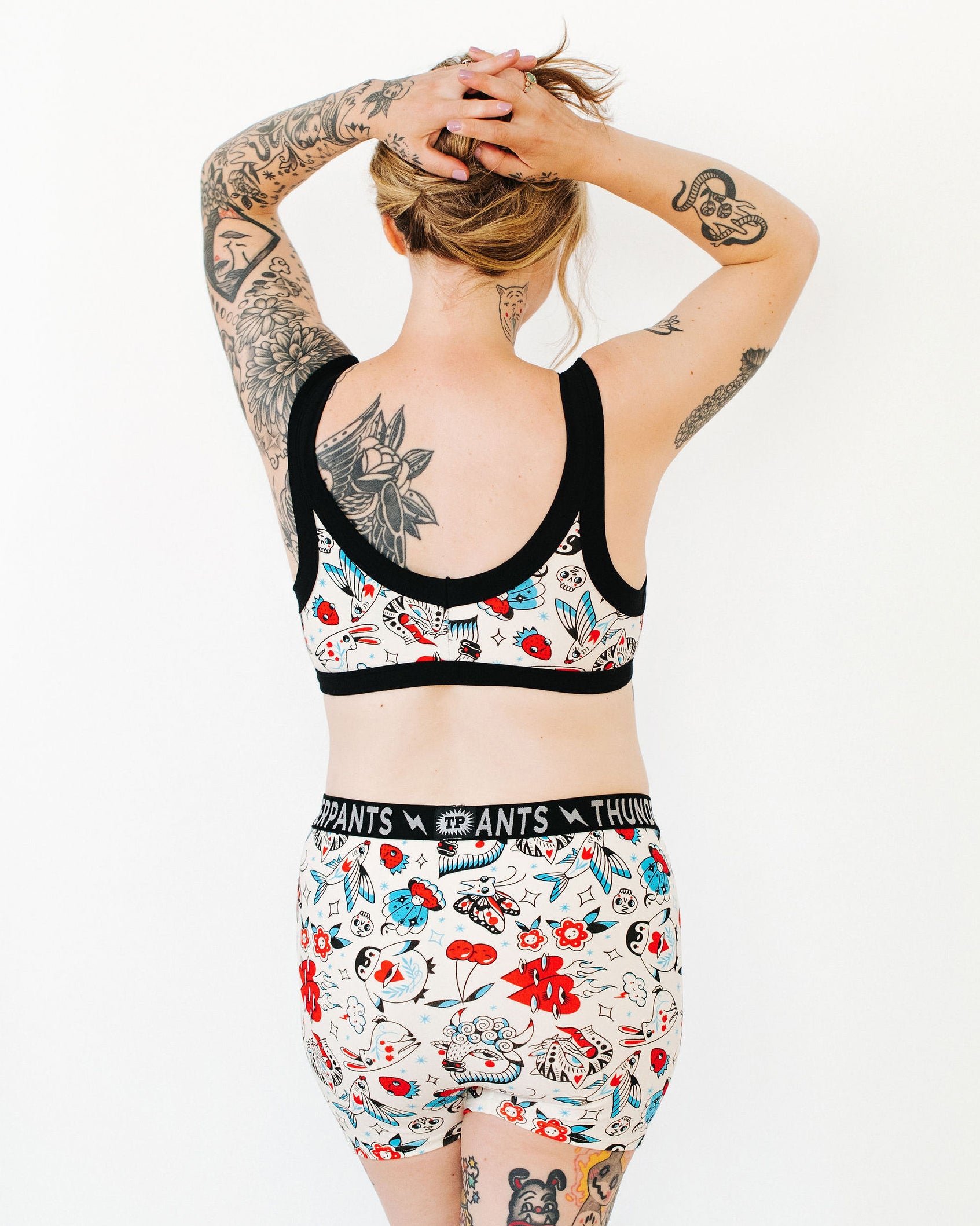 Model wearing Thunderpants Bralette and Boxer Brief style underwear in Inked Up - a tattoo pattern with black, red, and blue. 