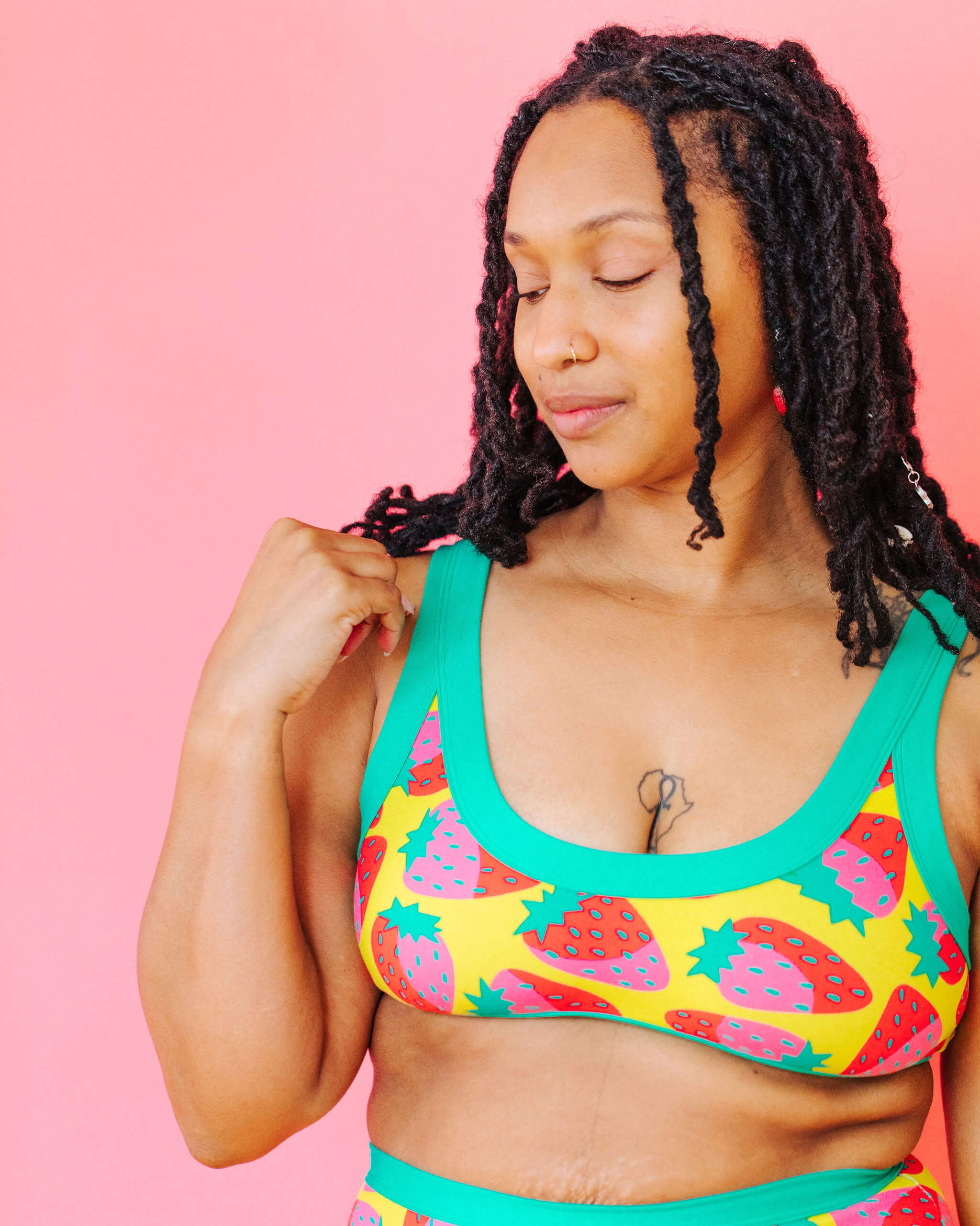 Model wearing Thunderpants Bralette in a Strawberry print - pink, red, and peacock green on chartreuse. 