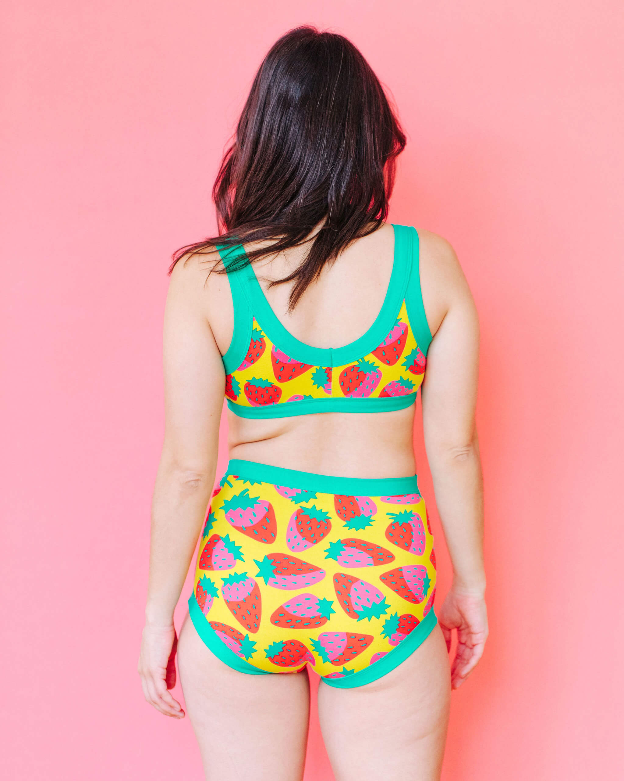 Model wearing Thunderpants Bralette and Sky Rise style underwear in a Strawberry print - pink, red, and peacock green on chartreuse. 