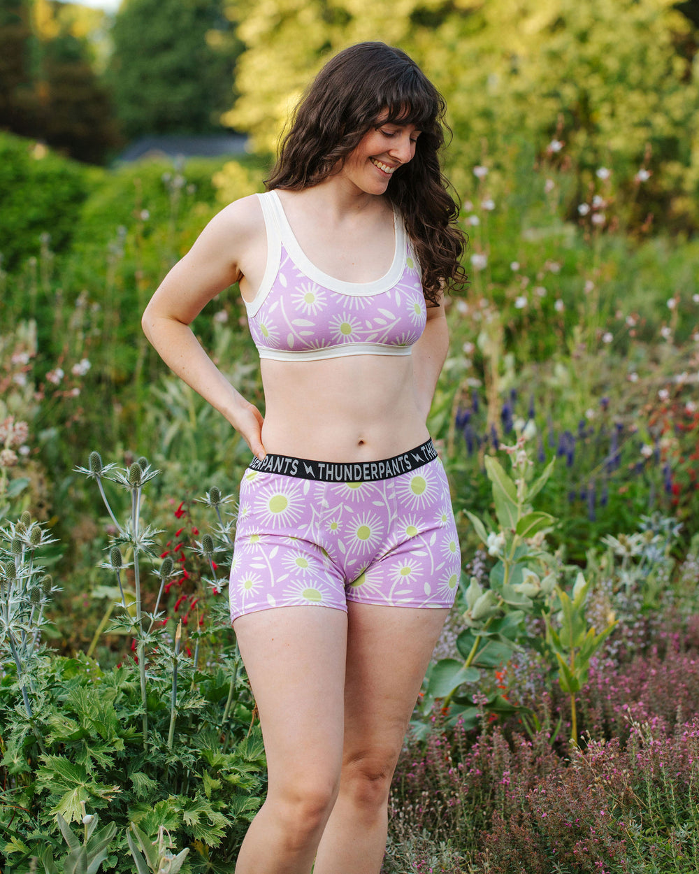 Model wearing Thunderpants Boxer Brief style underwear and Bralette in Delia's Daisy - white, green, and purple daisies print.