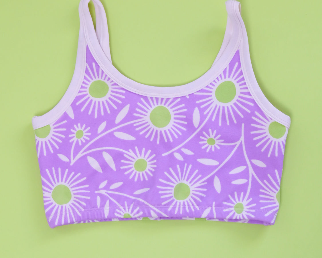 Flat lay of Thunderpants Longline Bra in Delia's Daisy - white, green, and purple daisies print.