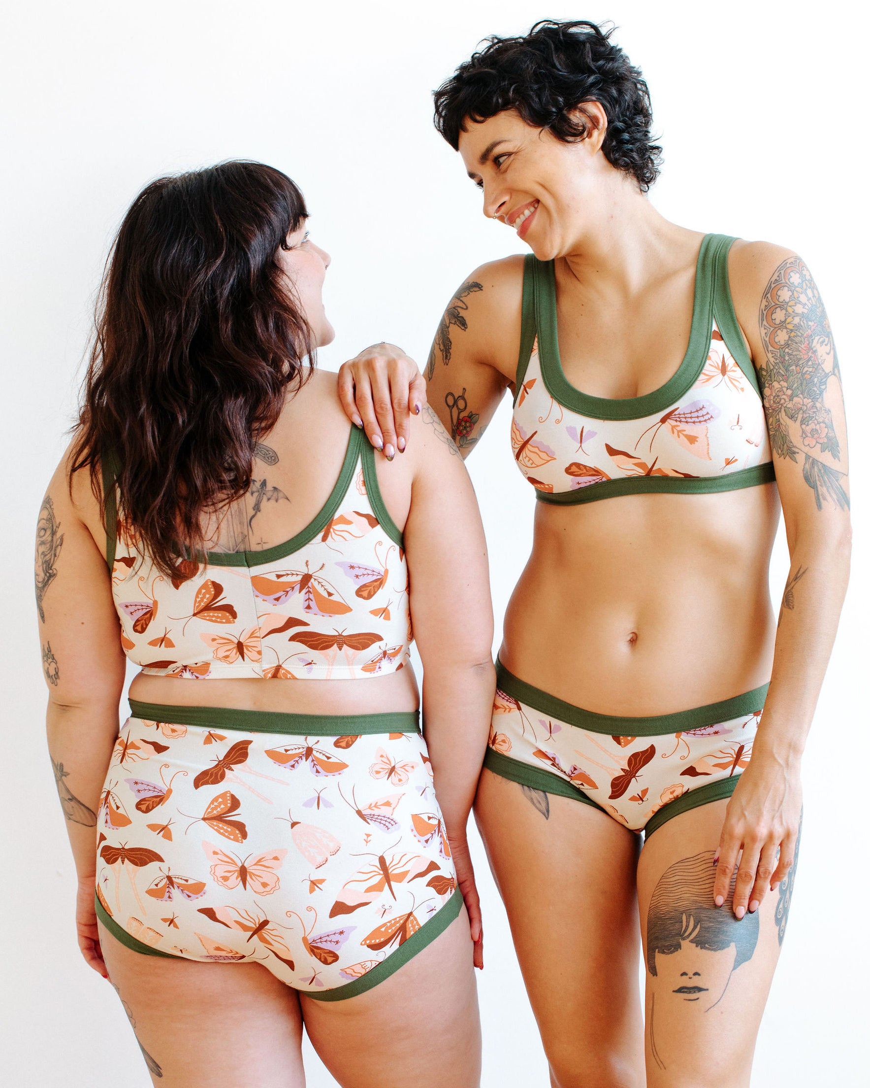 Models wearing Thunderpants Hipster style underwear and Bralette in Field Study: a moth print in red, orange, pink, and purple bound in green.