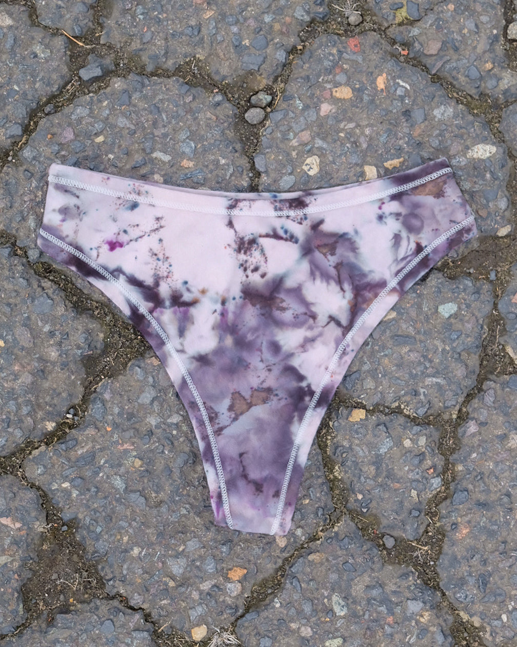 Flat lay of Thunderpants Thong style underwear in Haunted Haze Ice Dye - purply grey dye pattern.