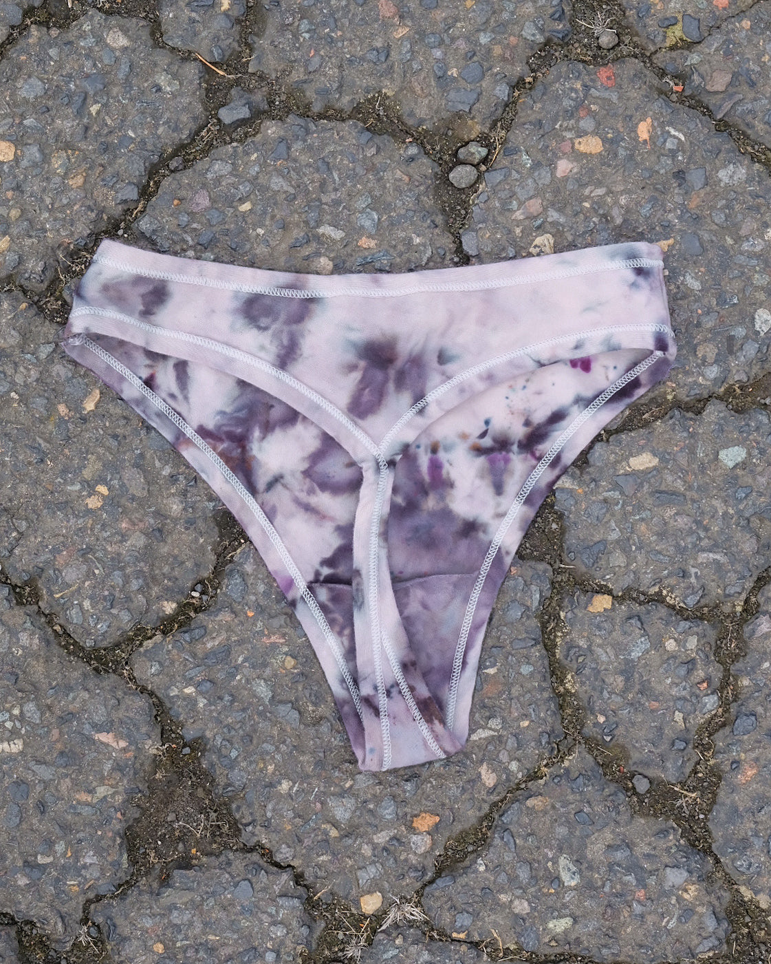 Flat lay of Thunderpants Thong style underwear in Haunted Haze Ice Dye - purply grey dye pattern.