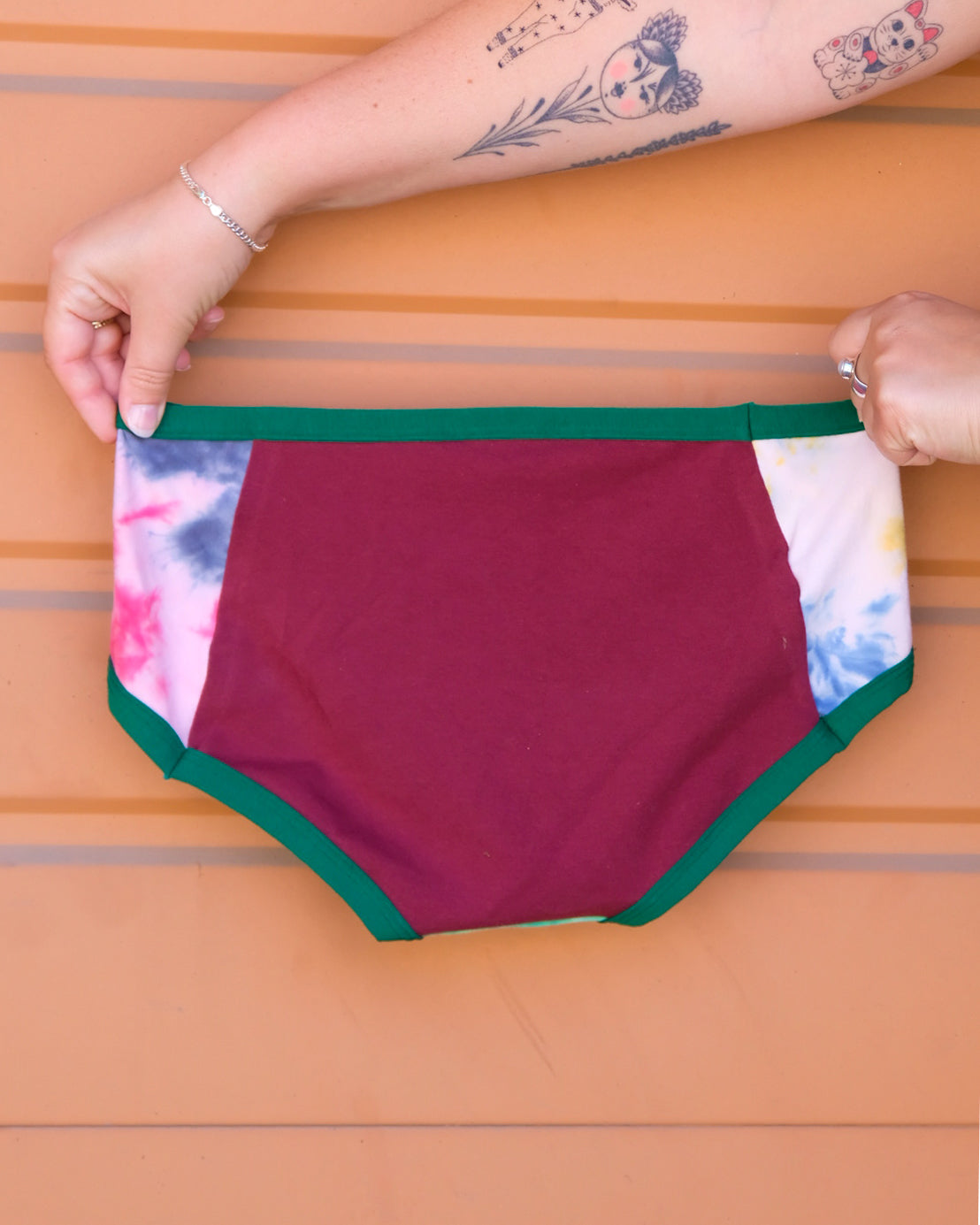 Hands holding a pair of Thunderpants Hipster style underwear in Dye Scrap Panel Pants - a mix of solids and dyed fabrics.