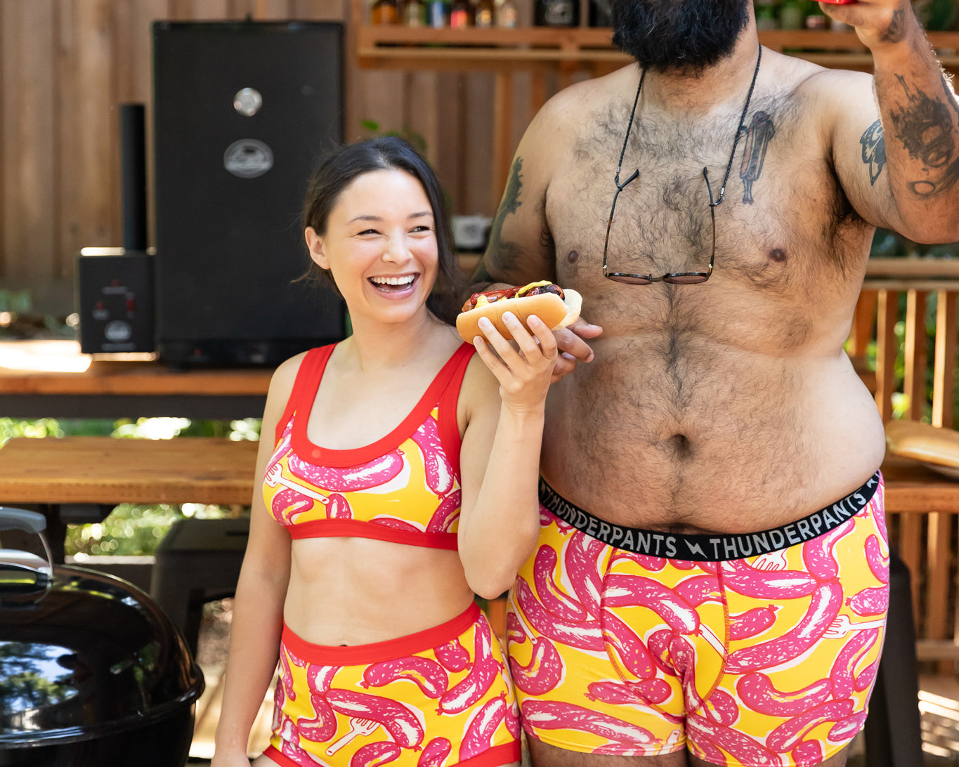 Models wearing Thunderpants Boxer Brief style underwear and other items in Hot Dawg! print - pink sausages on yellow background and red binding.