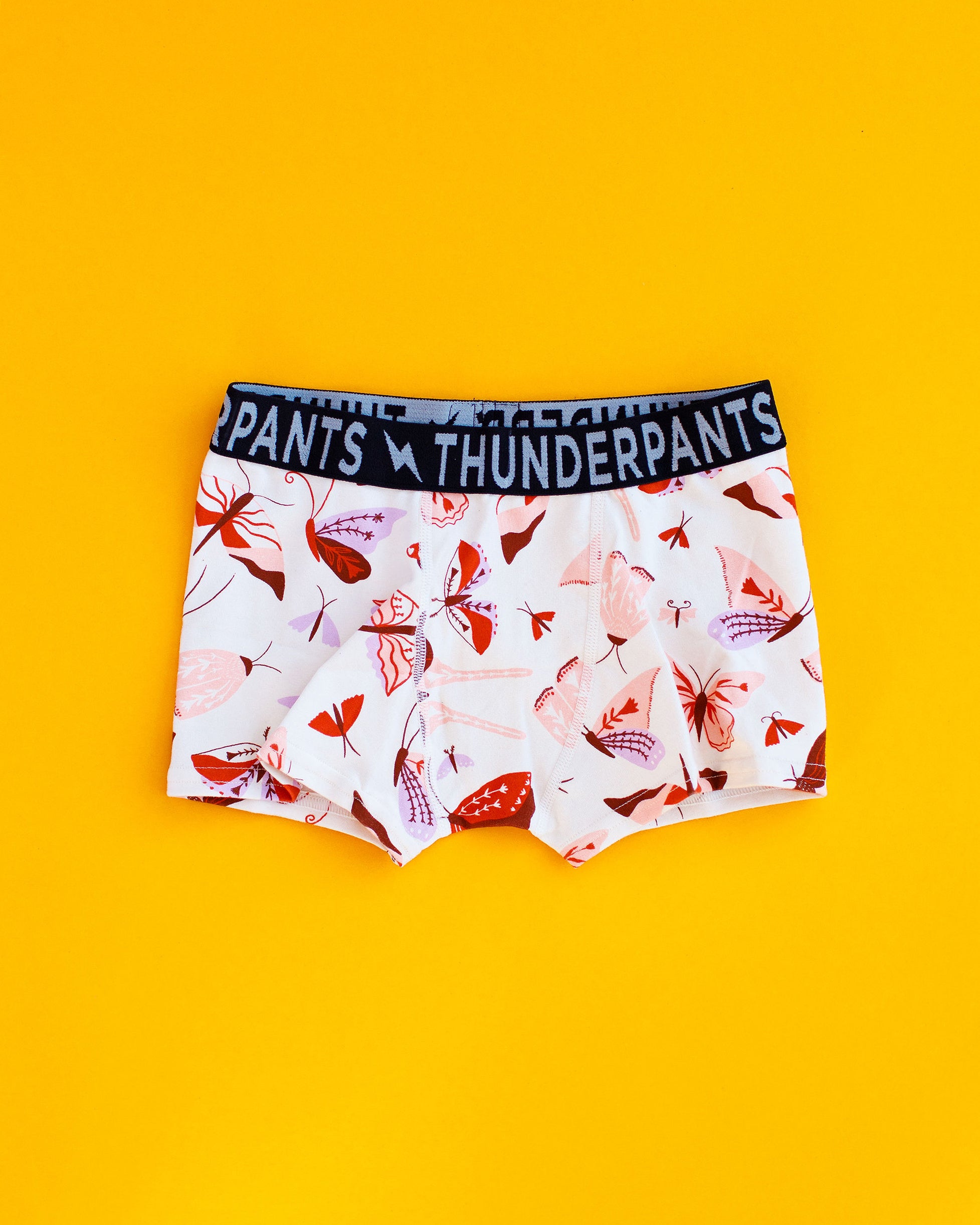 Flat lay of Kids Boxer Brief style underwear in Field Study - pink, brown, orange, and purple moths.