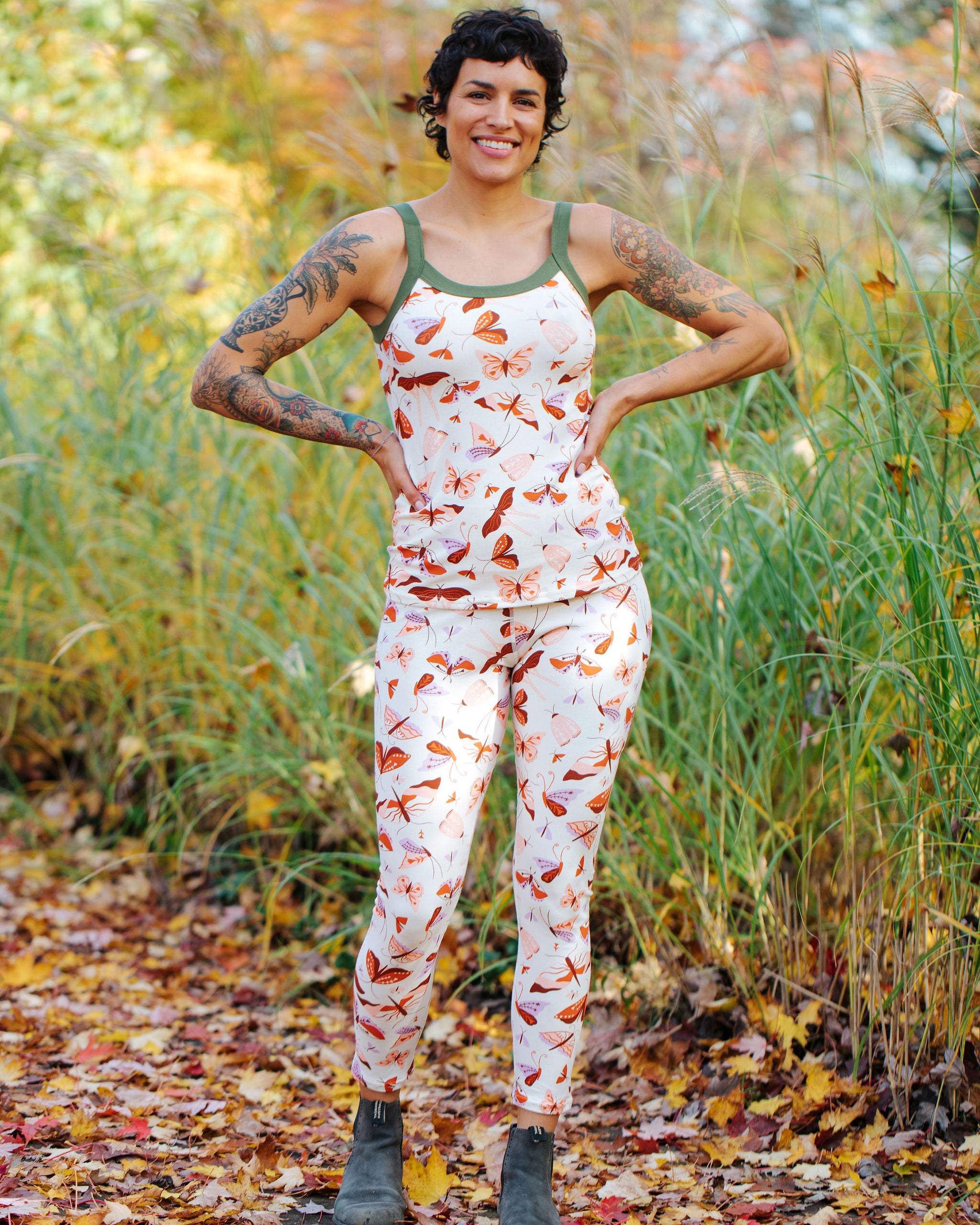 Model wearing Thunderpants Ankle Length Leggings and Cami in Field Study: a moth print in red, orange, pink, and purple bound in green.