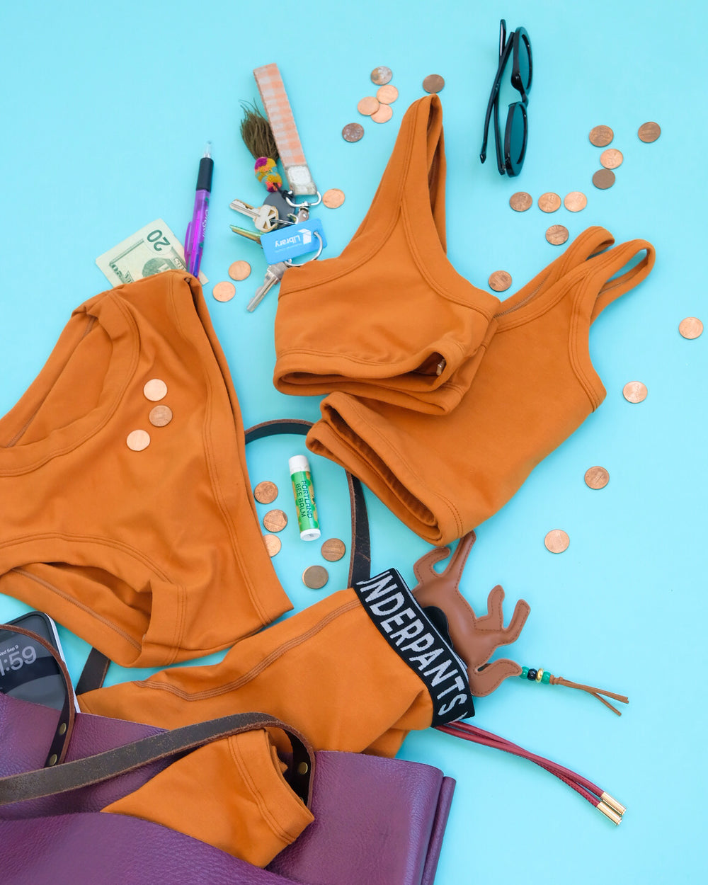 Flat lay of Thunderpants Longline Bra and other items in Lucky Penny - a rust color.