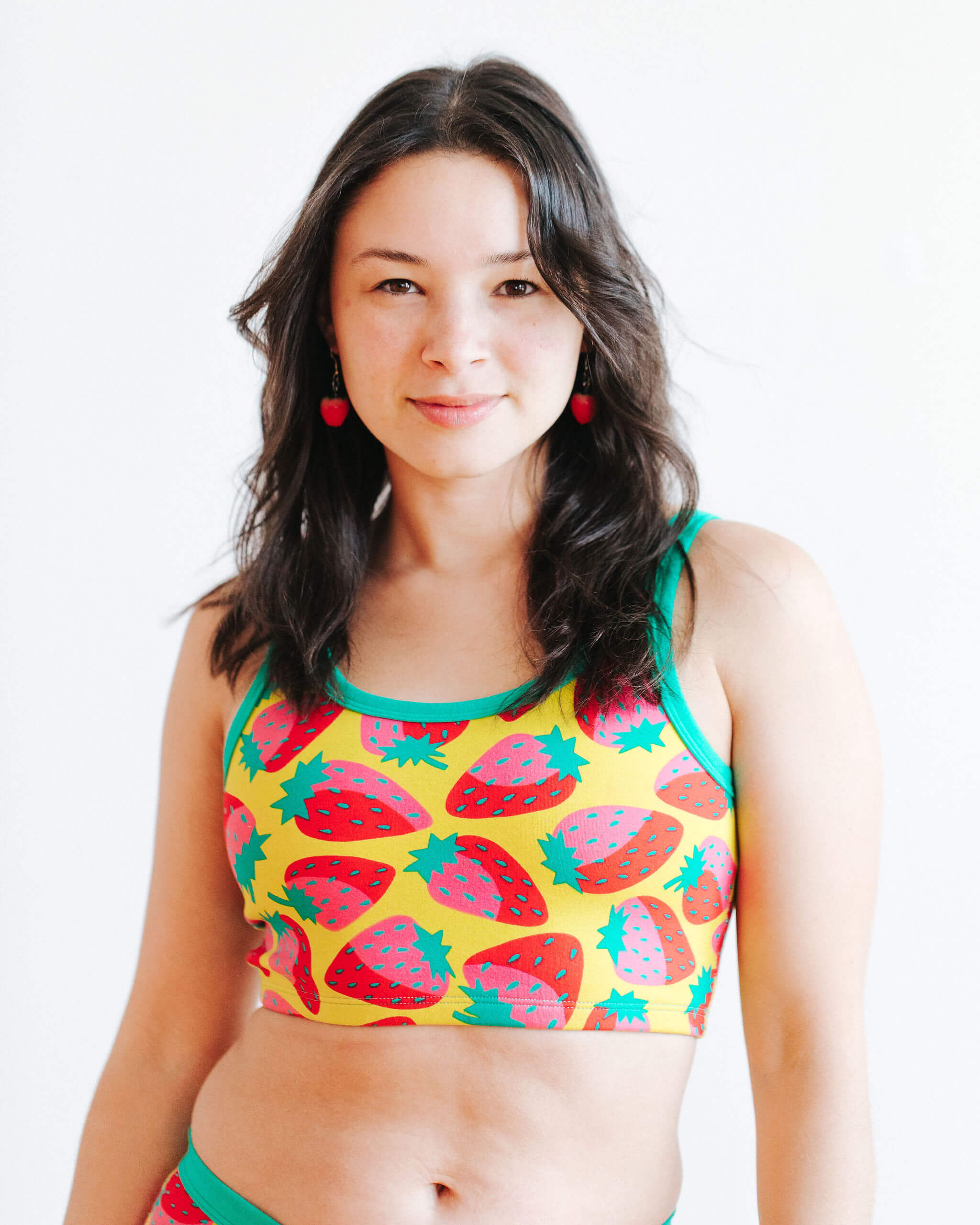 Model wearing Thunderpants Longline Bra in a Strawberry print - pink, red, and peacock green on chartreuse. 