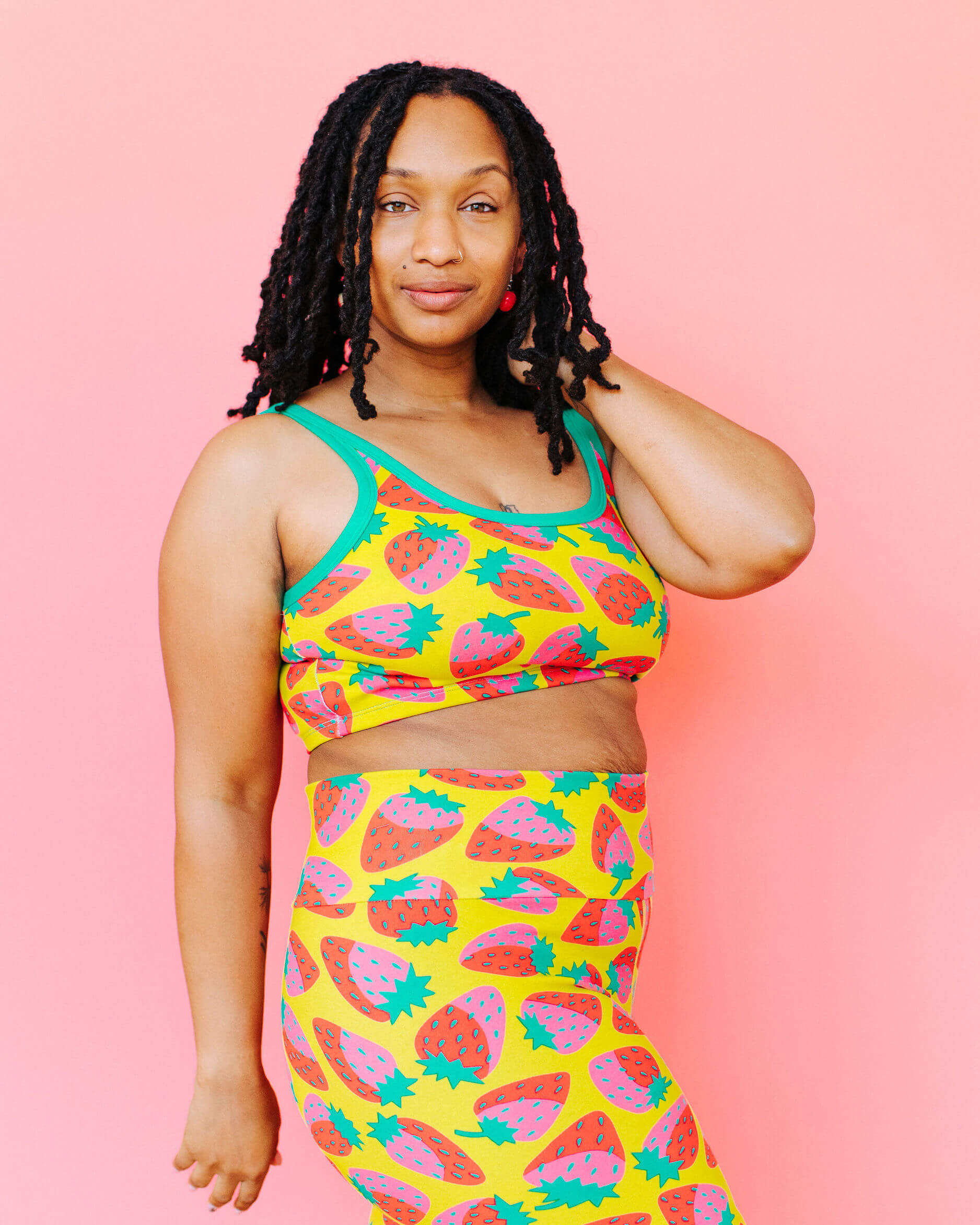 Model wearing Thunderpants Longline Bra in a Strawberry print - pink, red, and peacock green on chartreuse. 