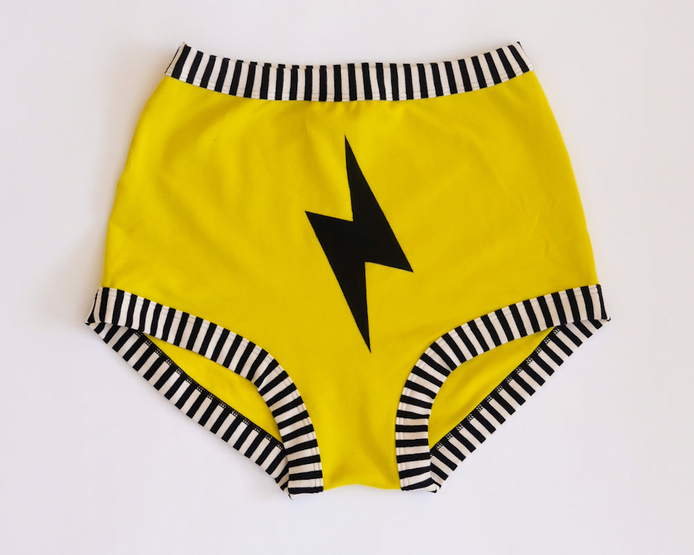 Flat lay of Thunderpants Sky Rise style underwear in Thunderstruck - yellow with a black lightning bolt.