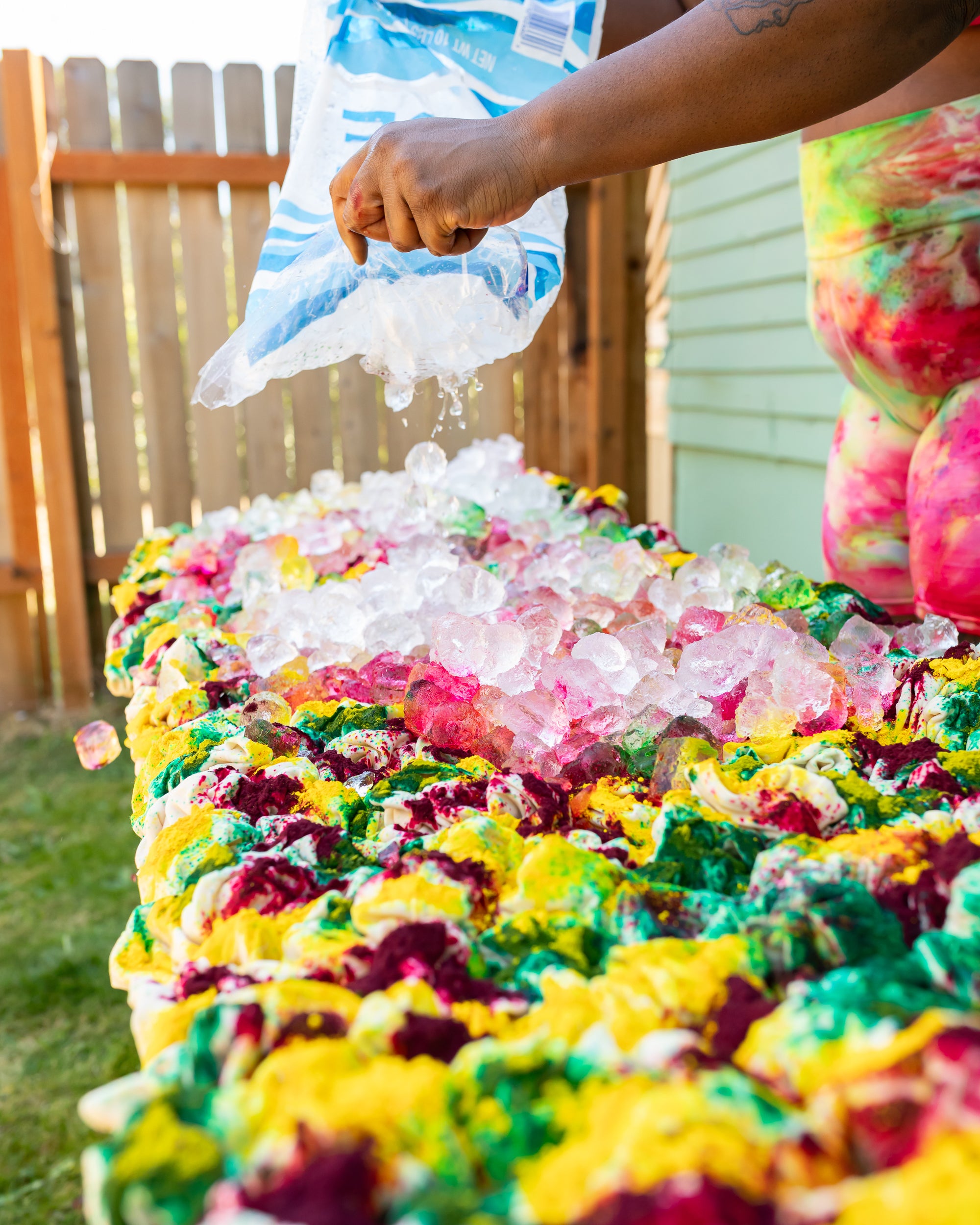 Ice being poured onto multiple colors of dye powder on bunched up underwear.