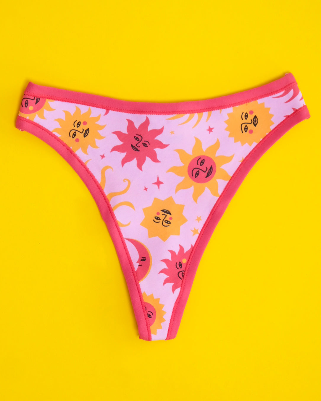 Flat lay of Thunderpants organic cotton thong style underwear in Luna y Sol print - pink and orange suns and moons.