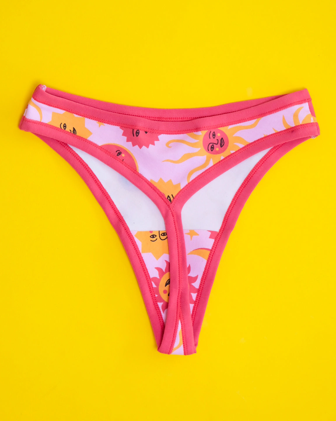Flat lay of Thunderpants organic cotton thong style underwear in Luna y Sol print - pink and orange suns and moons.