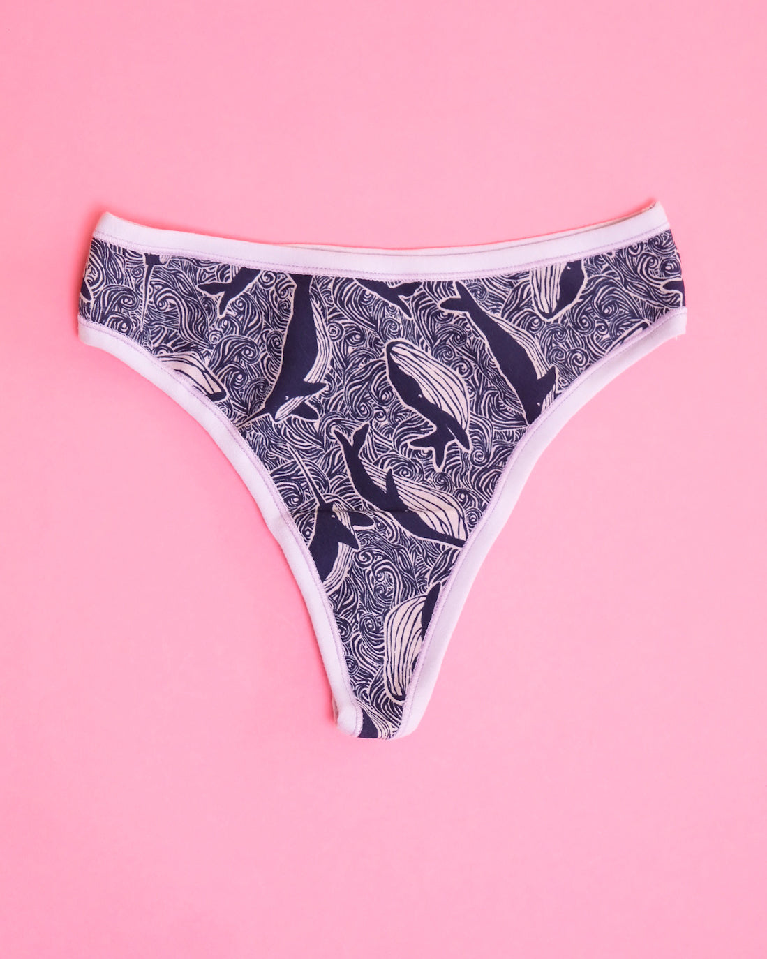 Flat lay of Thunderpants organic cotton thong style underwear in blue and light purple whale print.