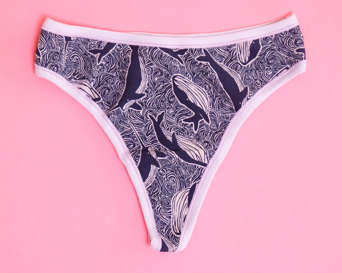 Flat lay of Thunderpants organic cotton thong style underwear in blue and light purple whale print.