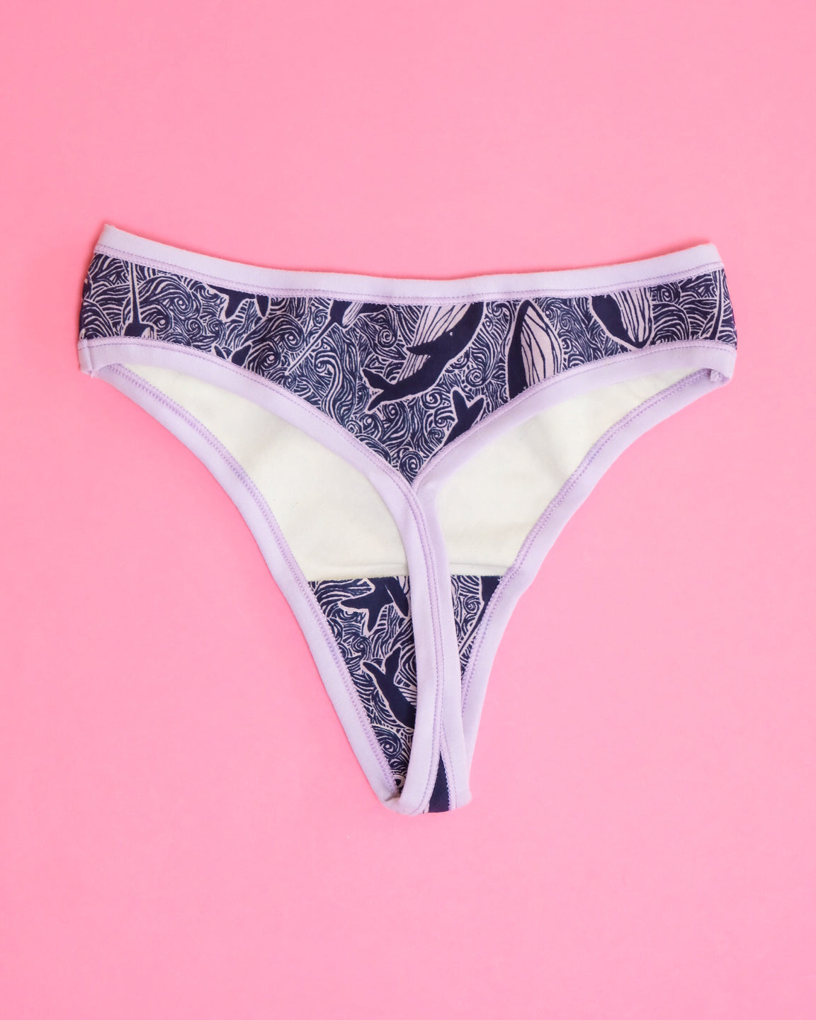 Flat lay of Thunderpants organic cotton thong style underwear in blue and light purple whale print.