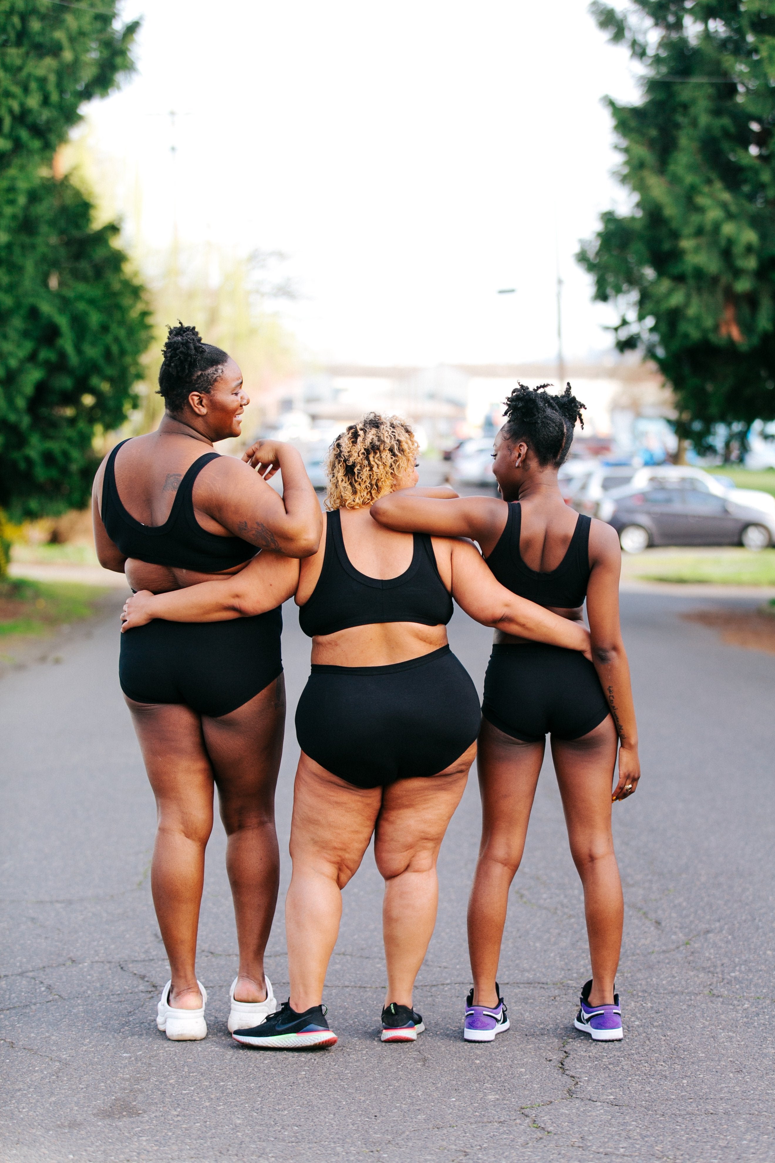 Three models standing together with their backs towards us wearing Thunderpants Organic Cotton Original style underwear and Bralettes in plain Black color.